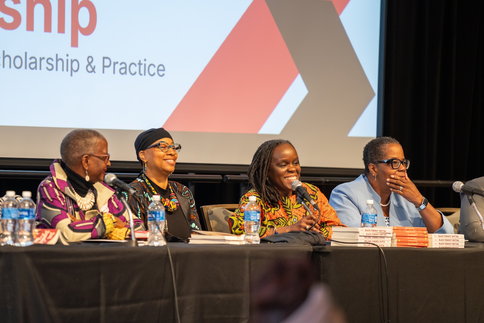 four females sitting behind a table with microphones