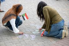 People write a message on Hornbake Plaza with chalk during the vigil 